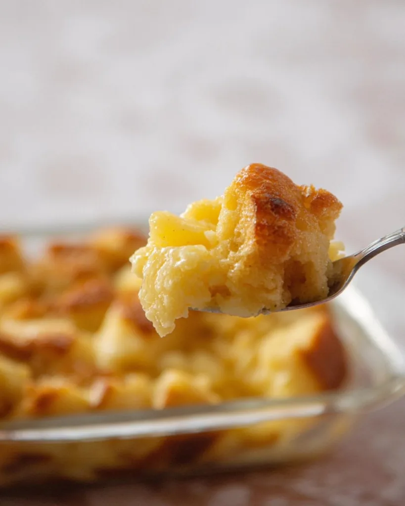 Spoon lifting a bite of pineapple casserole with golden bread