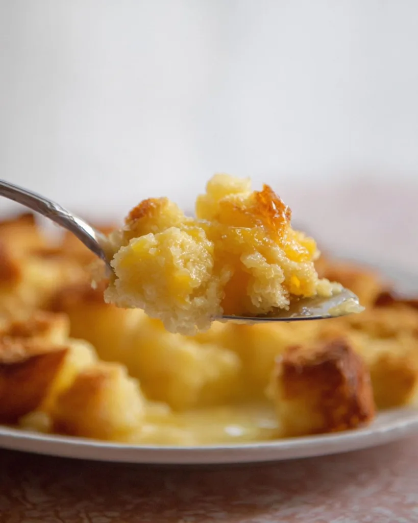 A spoonful of baked pineapple casserole with bread served hot
