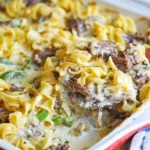 Philly cheesesteak casserole with steak, noodles, and cheese in baking dish