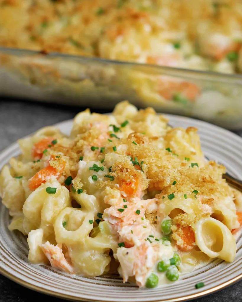 salmon noodle casserole on plate with cheesy topping and chives